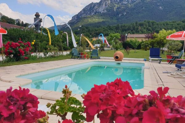 Une sc&egrave;ne estivale vibrante avec une tranche de tranquillit&eacute; due &agrave; une piscine, entour&eacute;e de toboggans et de chaises color&eacute;es, le tout dans un