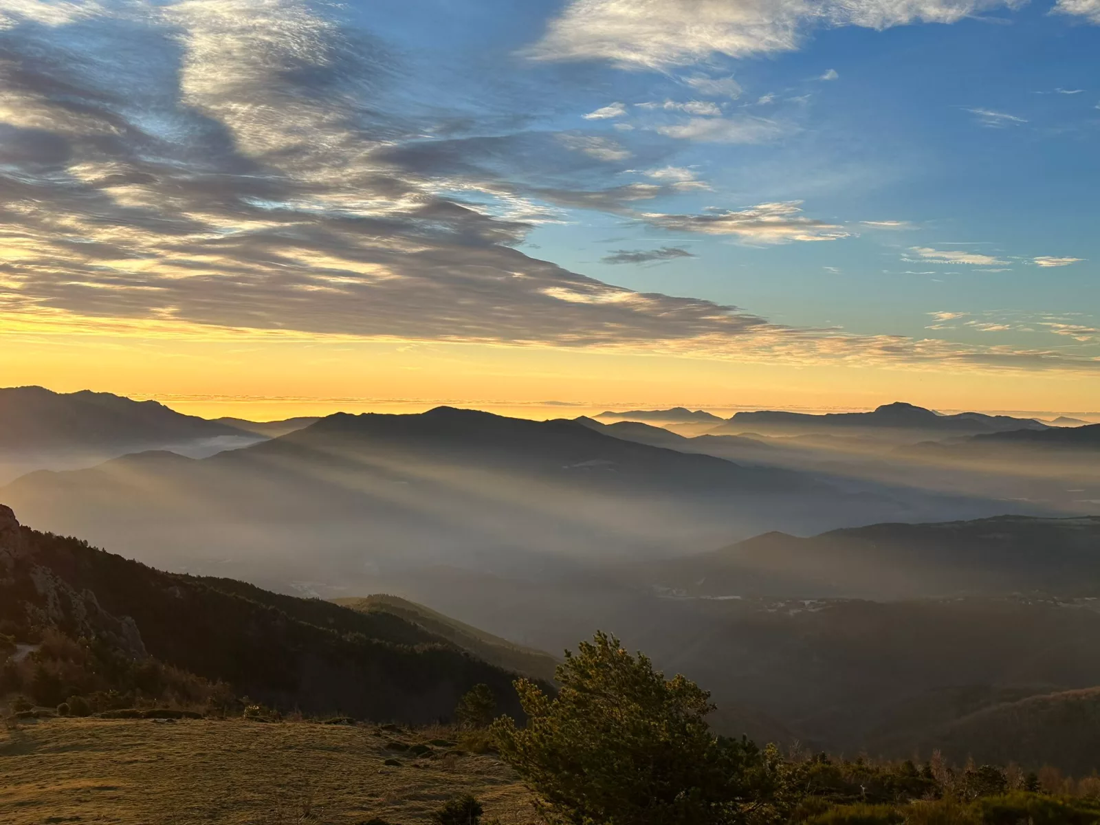 Un voyageur capture la beauté d'une mer de nuages au coucher du soleil depuis un point de vue de haute montagne, offrant un accueil fascinant à la soirée.