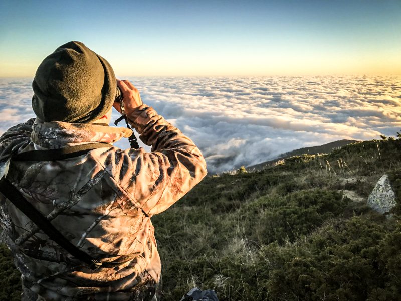 Un voyageur capture la beauté d'une mer de nuages au coucher du soleil depuis un point de vue de haute montagne, offrant un accueil fascinant à la soirée.