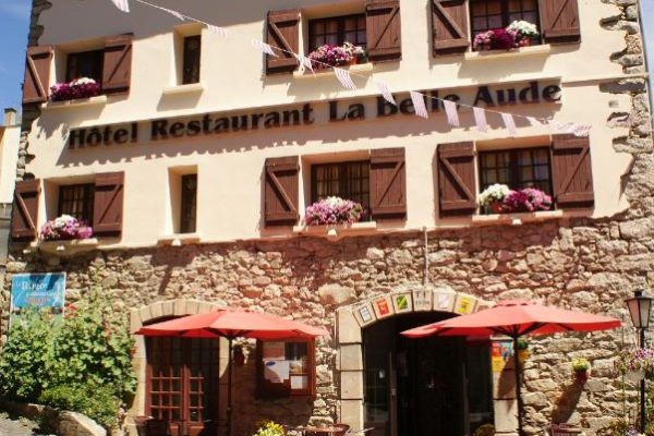 Un encantador hotel europeo con una pintoresca fachada adornada con jardineras, banderas de colores y un acogedor café a pie de calle, perfecto para los aficionados a la caza de fin de semana.