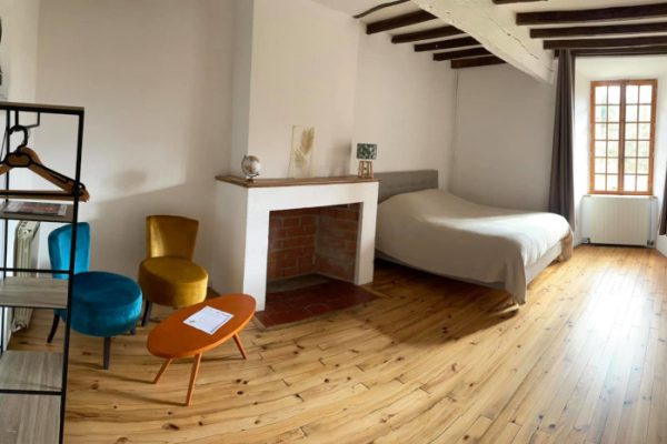 Une chambre lumineuse et cosy au design minimaliste, idéale pour un week-end chasse dans les Pyrénées, comprenant un lit simple, un petit espace de travail près de la fenêtre, un parquet au sol,