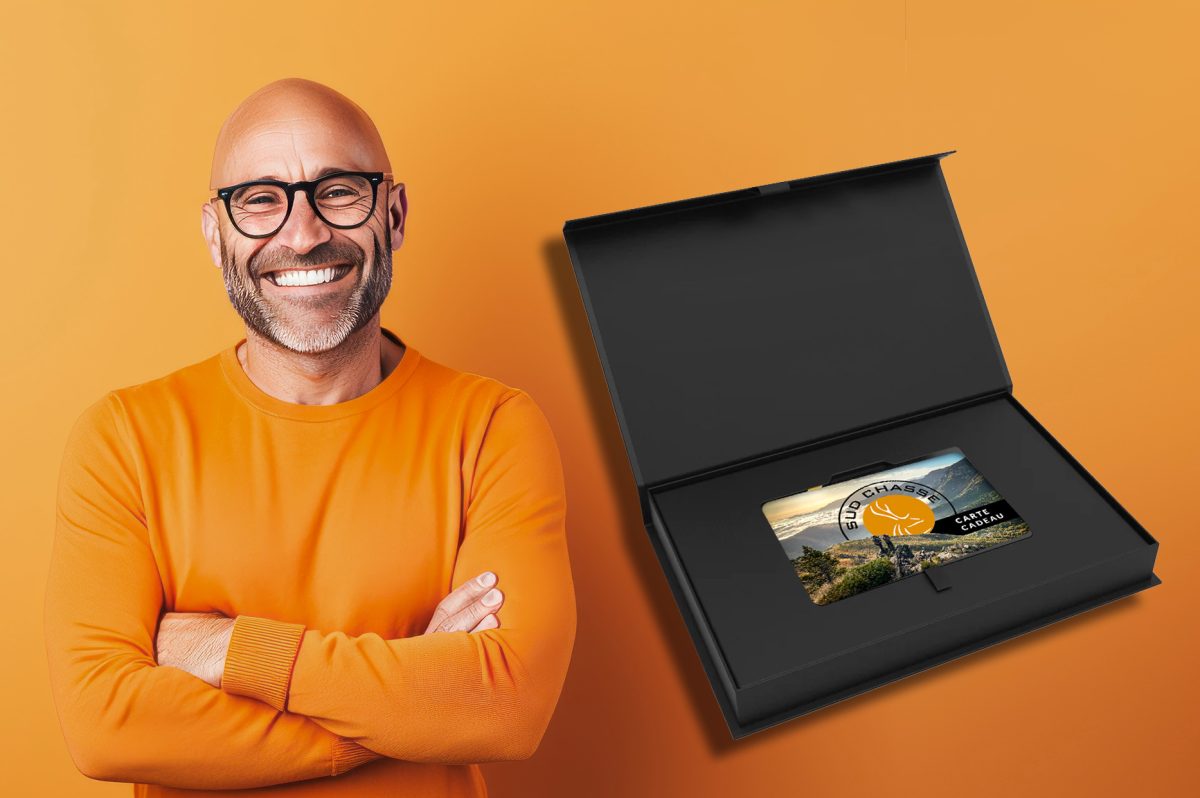 Un homme souriant en pull orange présente fièrement une carte-cadeau sur un fond orange vif.
